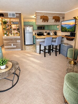 Una cocina moderna con una isla de madera, taburetes de bar y un televisor de pantalla plana.