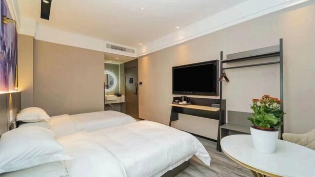 A hotel room with two beds, a TV, a small table, and a potted plant. - Shanghai Evening Fenglin Hotel (Shanghai)