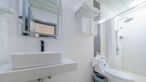 A modern bathroom with a white sink, mirror, and toilet. There is a shower area with a glass door and a towel rack above the sink. - Shanghai Evening Fenglin Hotel (Shanghai)