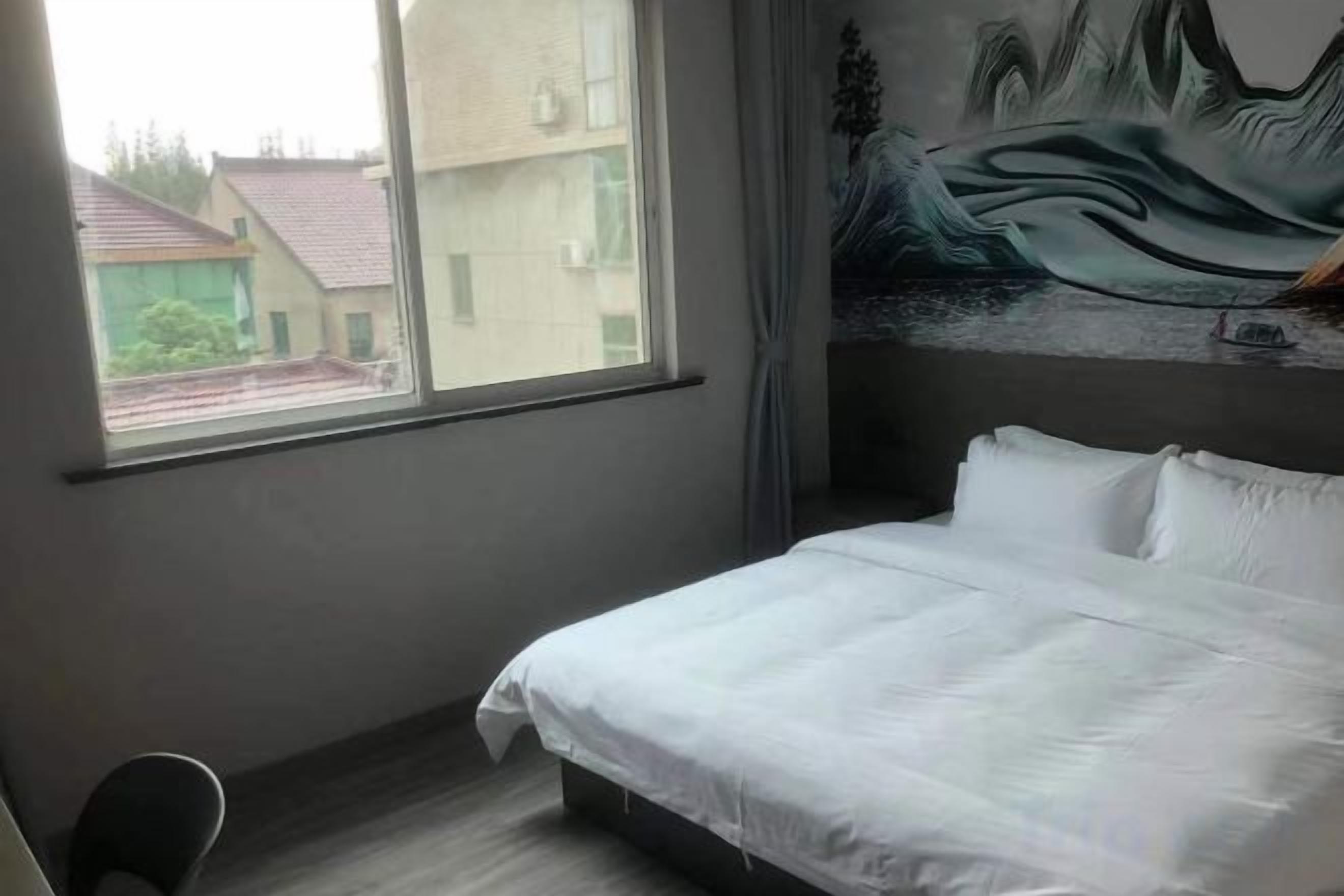 Una habitación de hotel con una cama, un ventanal y un mural en la pared.