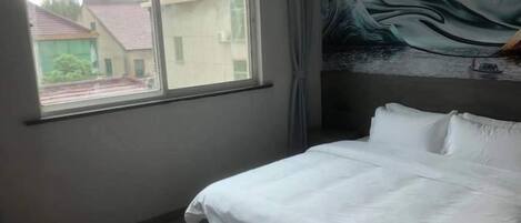 Una habitación de hotel con una cama, un ventanal y un mural en la pared.