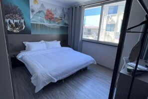 Une chambre d’hôtel avec un lit, une fenêtre et une fresque murale.