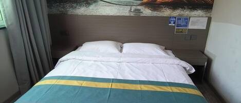 Quarto de hotel com cama, mesa de cabeceira e uma parede com um quadro.