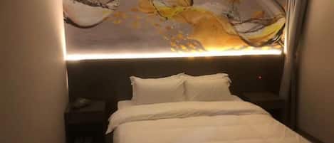 Habitación de hotel con una cama, una mesita de noche y una lámpara de pared.