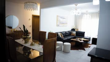 Relax in a stylish living space with a dining area and seating area, featuring a round mirror, vase, and table with chairs, as well as a sofa, coffee table, and cowhide rug.
