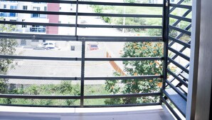 Un balcon donnant sur des immeubles et un parking.