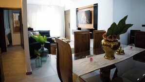 Un comedor moderno con una mesa de vidrio, sillas de madera y un jarrón decorativo con flores.