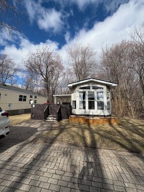 Traditional home with a bay window and attached cottage, set amidst mature trees in a peaceful wooded area.