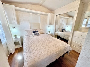 Relax in a serene bedroom with a large bed, nightstand, and dresser, perfect for a restful stay.