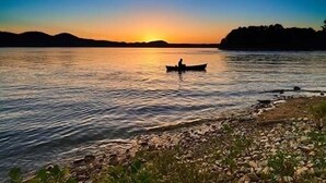 A calm river at sunset with a boat in the middle.
