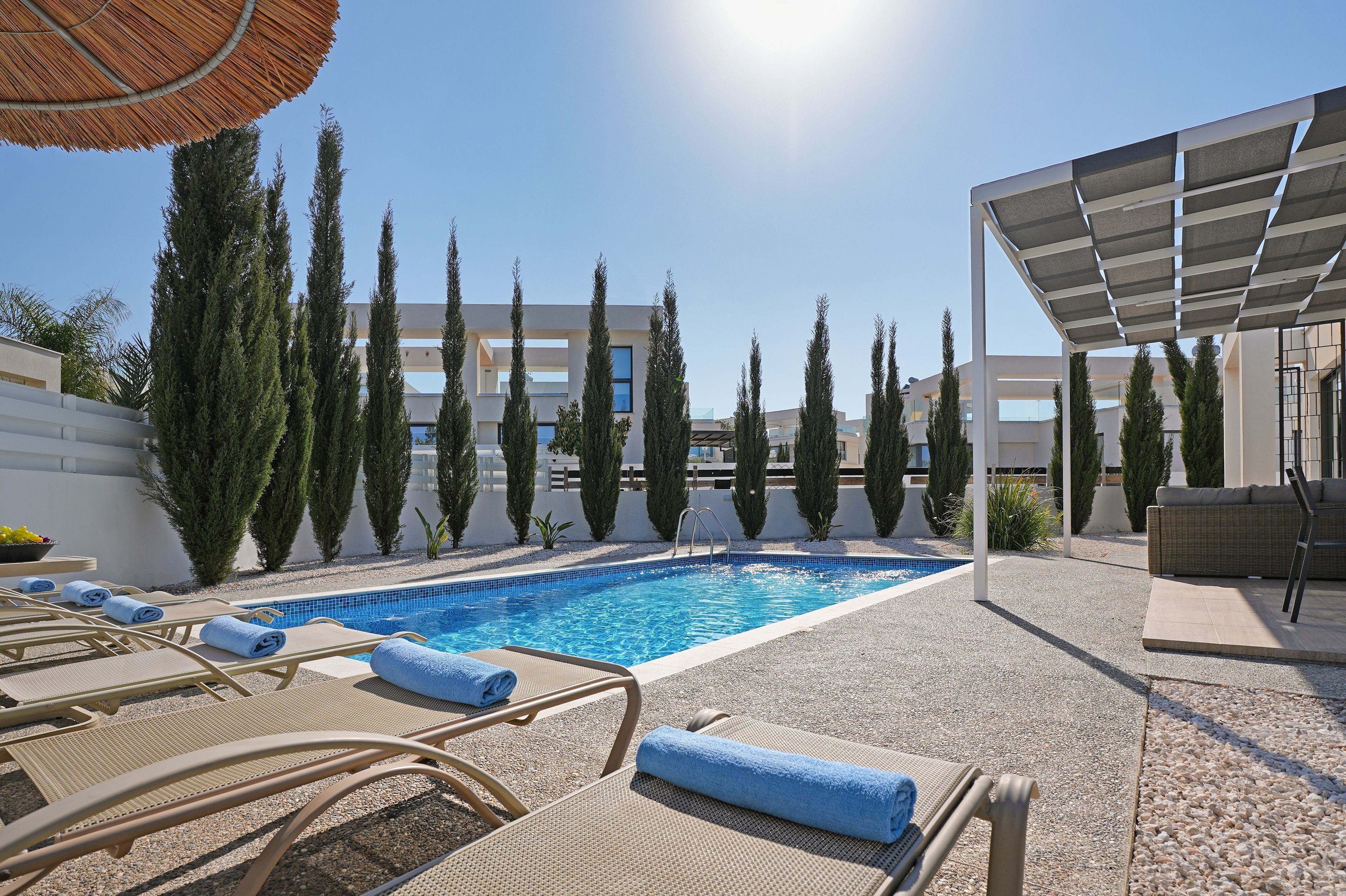 A pool area with lounge chairs and a pergola.