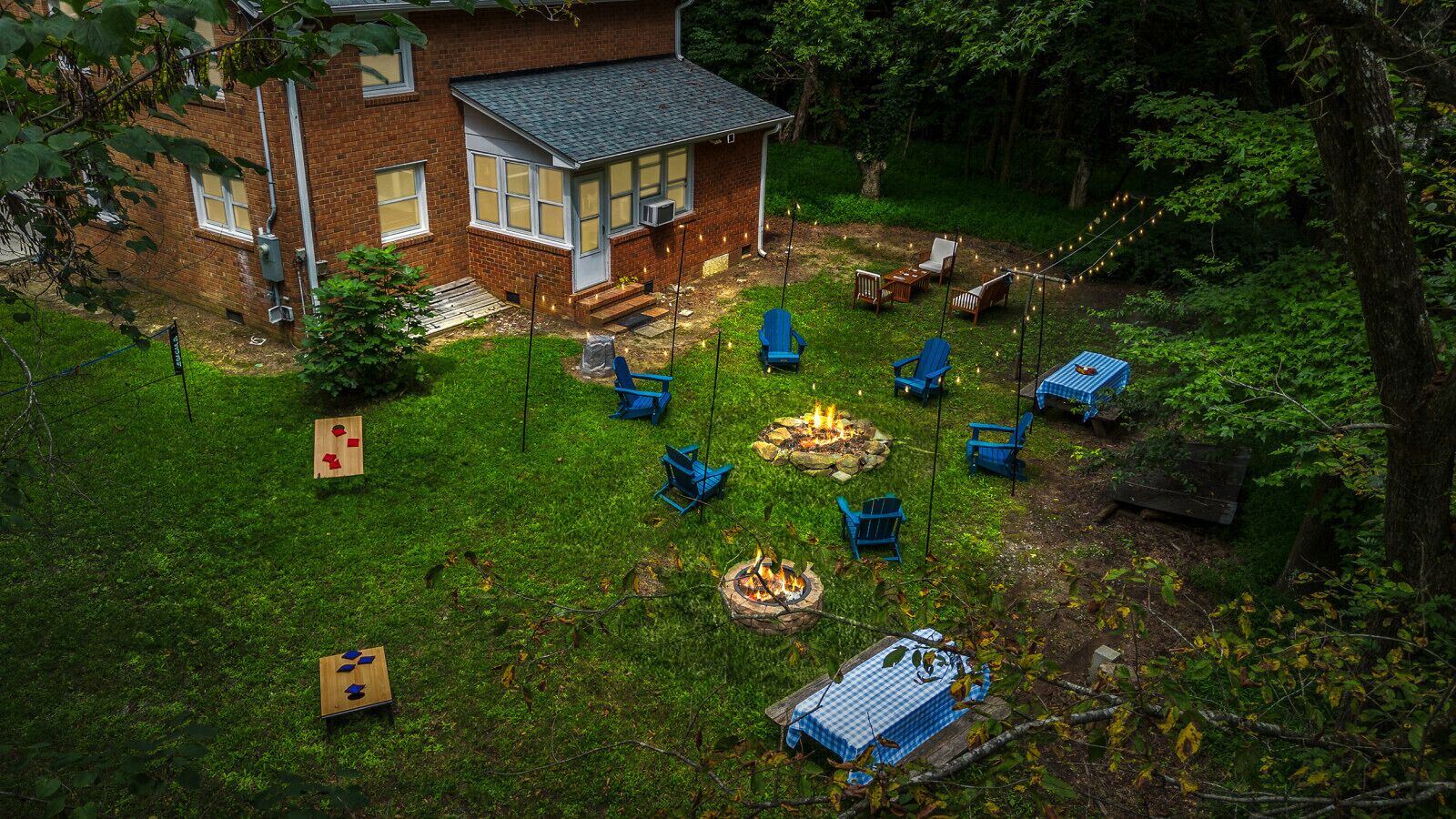 A backyard with a brick house, a fire pit, and blue chairs.