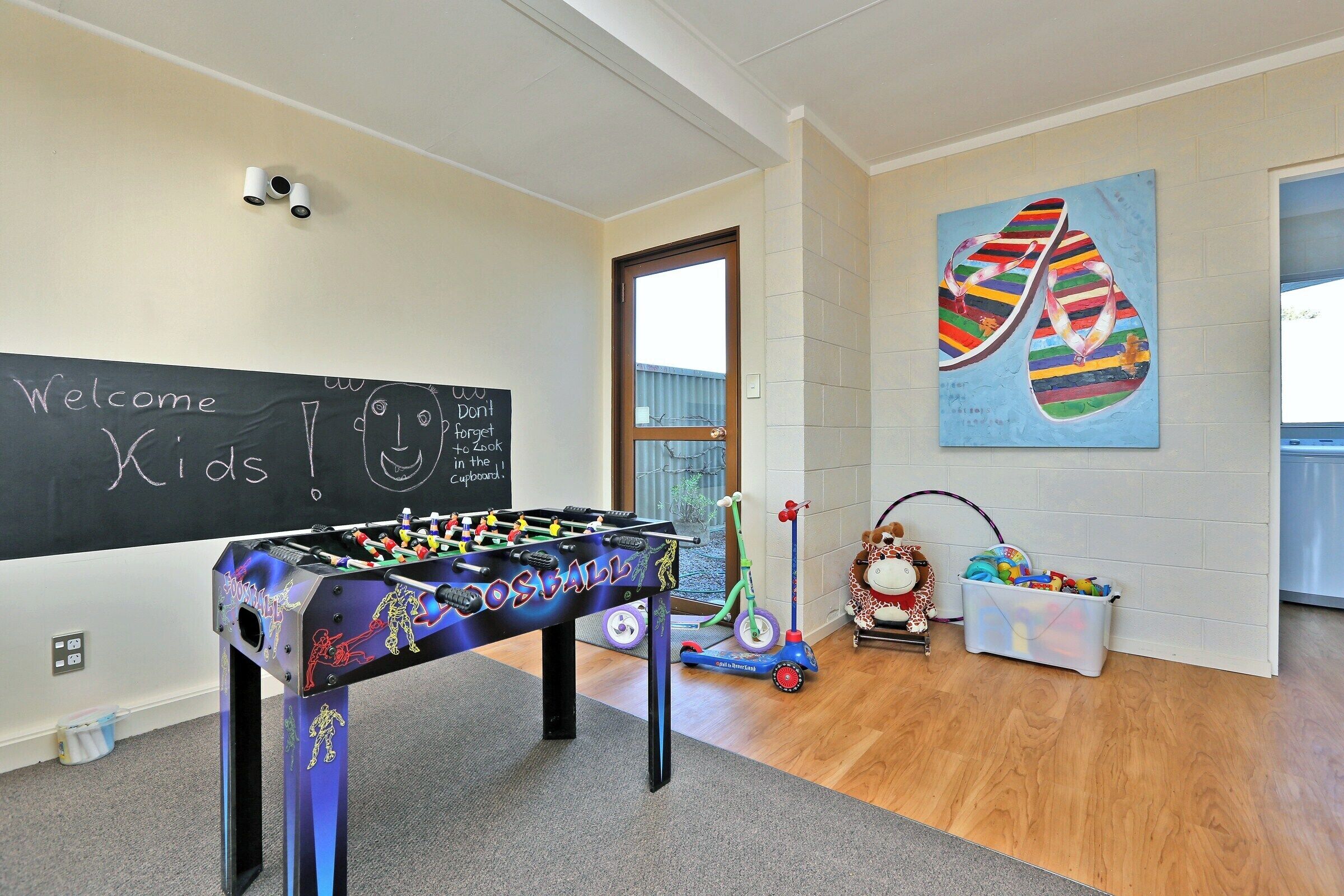 Une pièce avec un baby-foot, un tableau noir orné de dessins et des jouets pour enfants.