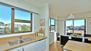 Una cocina moderna con un amplio ventanal, un lavamanos y una zona de comedor con mesa y sillas.