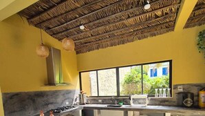 A kitchen with a central island, bar stools, a gas stove, and a large window.