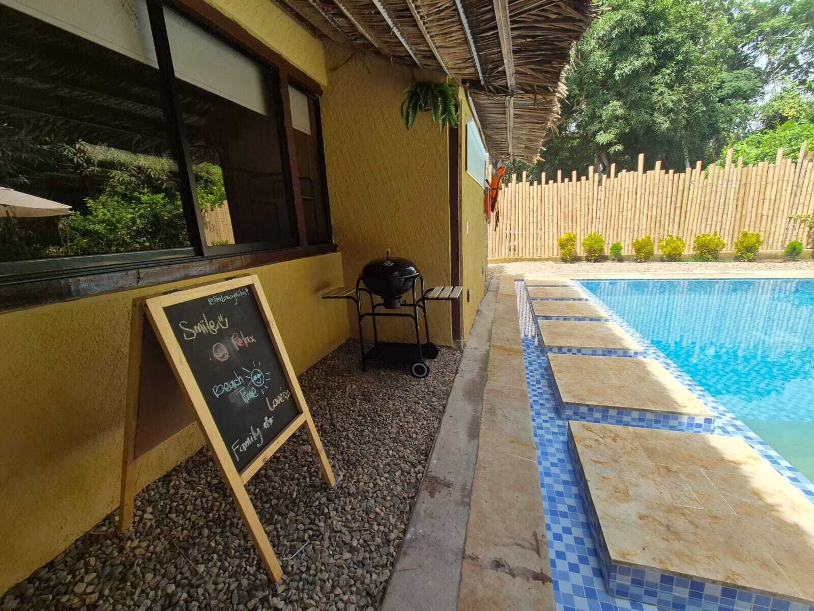 Een zwembadgedeelte met een schoolbord, een barbecue en een houten omheining.
