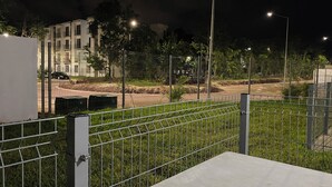Ein von einer Hecke umgebener Außenbereich mit befestigtem Weg, umgeben von Pflanzen und einem Gebäude im Hintergrund.