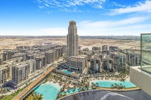 A high-rise building with a prominent tower, surrounded by residential buildings and a large swimming pool complex.