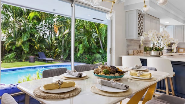 A dining area with a view of a swimming pool and lush greenery. - Chic 3 BR Villa with Private Pool – Fort Lauderdale (Fort Lauderdale)
