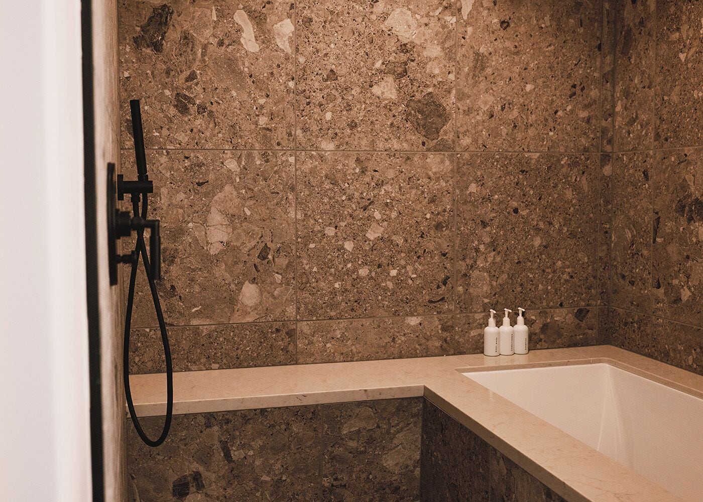 Une salle de bain avec un mur en marbre, une baignoire et une douche.