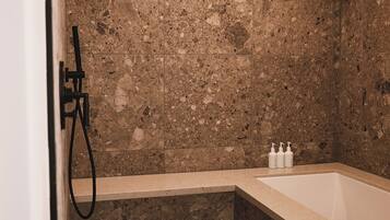 Une salle de bain avec un mur en marbre, une baignoire et une douche.
