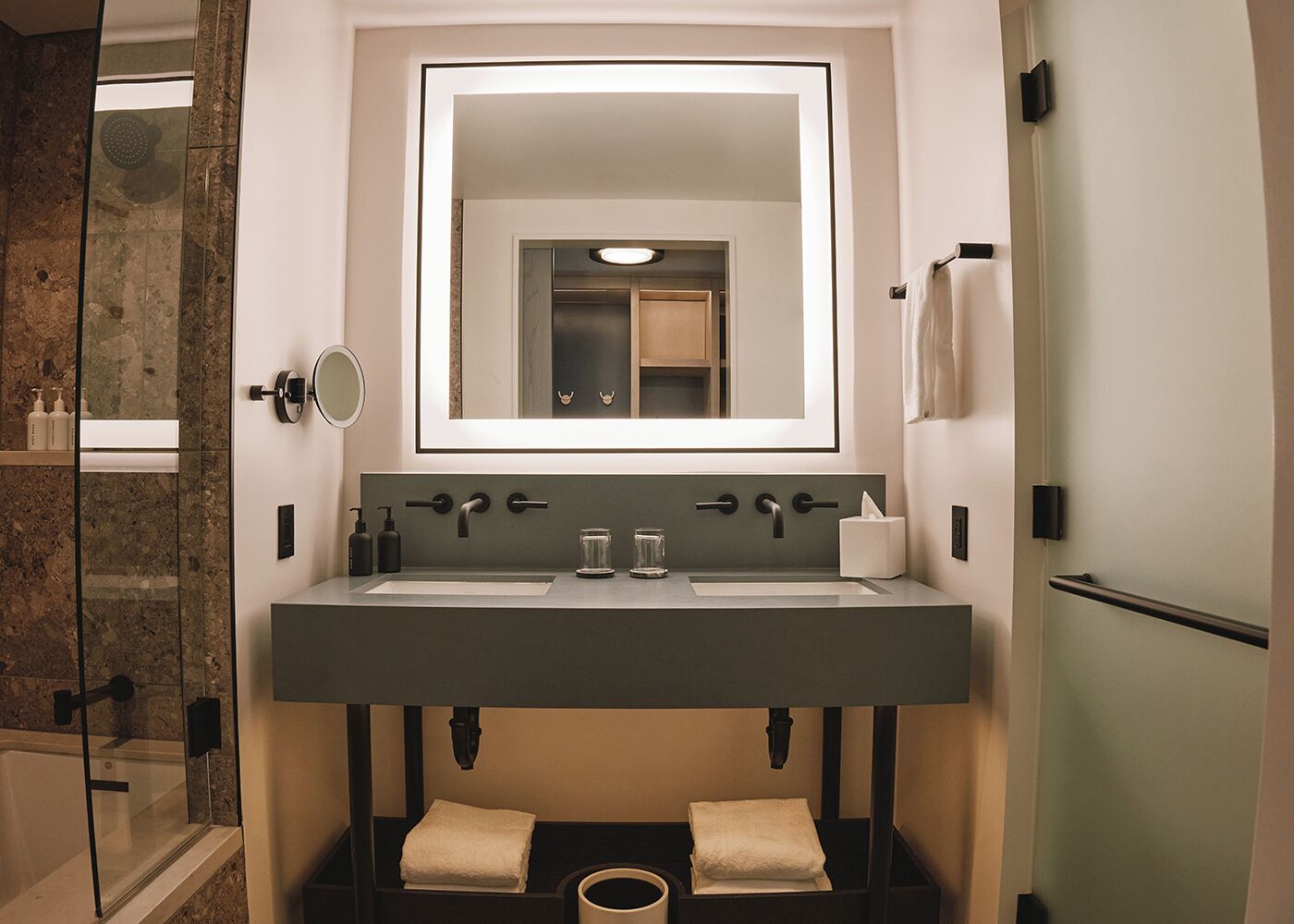 A modern bathroom with a dual sink vanity, a large mirror, and a built-in toilet.
