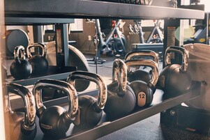 Una hilera de mancuernas en un estante dentro de un gimnasio.