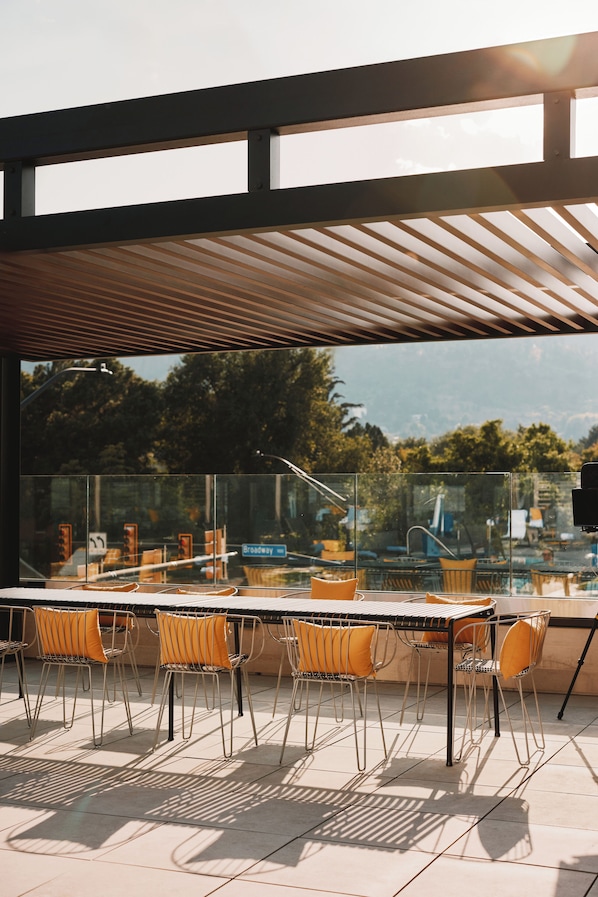 A rooftop terrace with a glass railing, outdoor seating, and a view of the cityscape. - Limelight Boulder (Boulder)