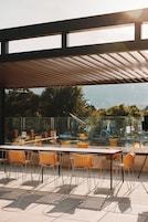 Una terraza en la azotea con barandilla de cristal, mobiliario exterior y vistas a la ciudad.