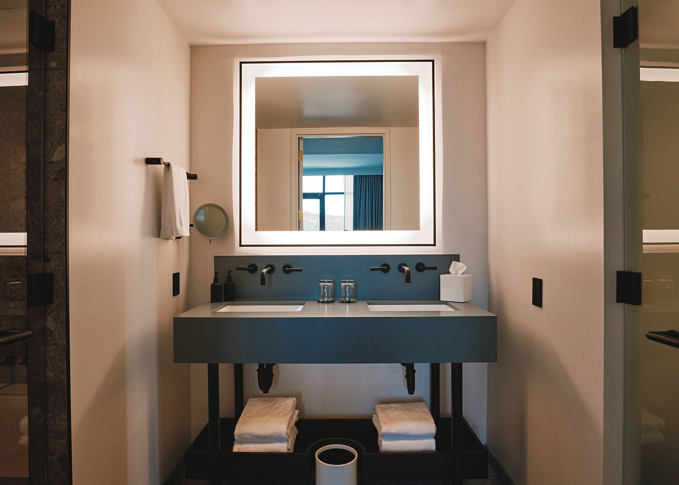A modern bathroom with a large mirror, two sinks, and a towel rack.