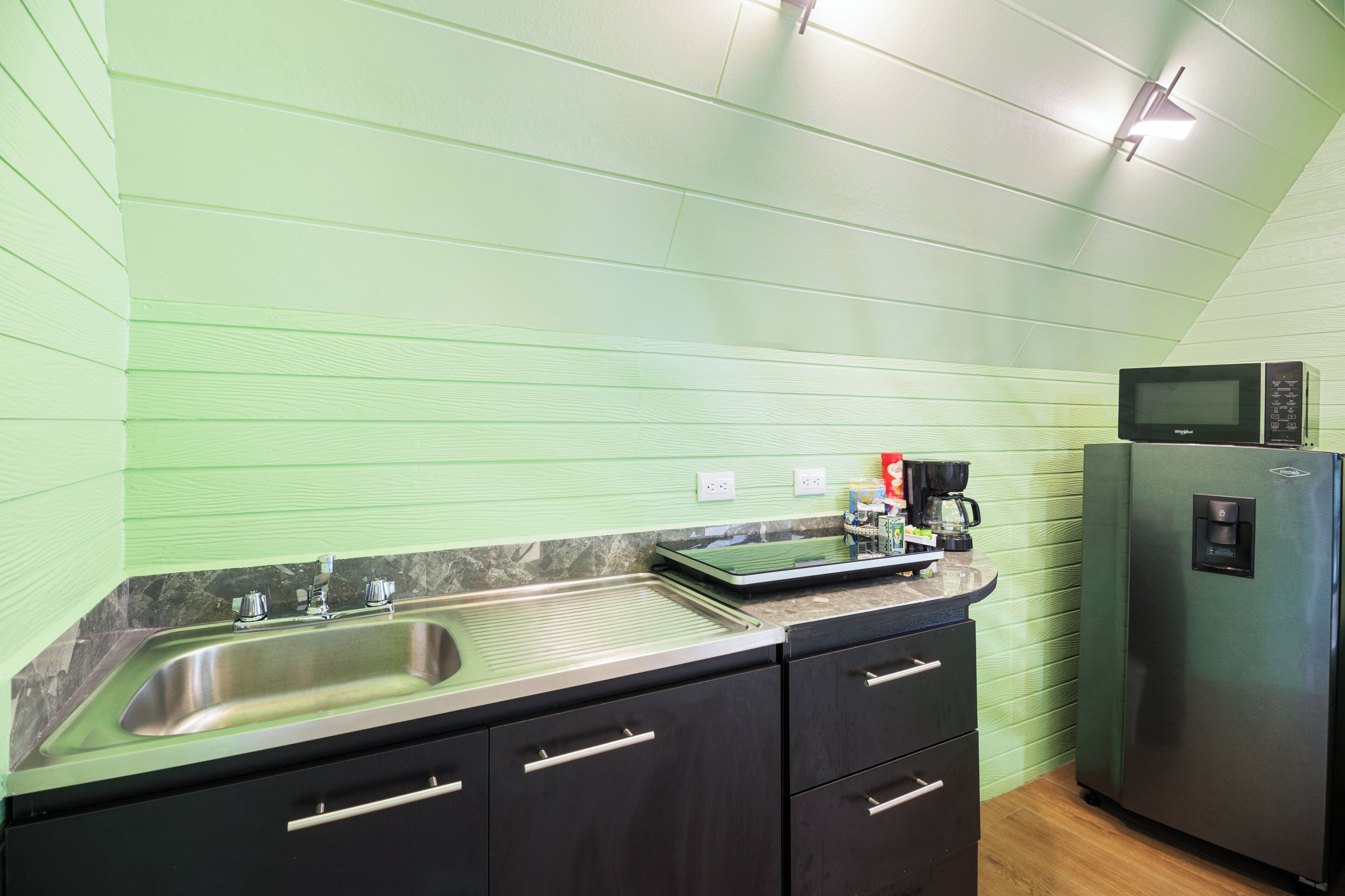A kitchen with a stainless steel sink, a microwave, and a refrigerator.