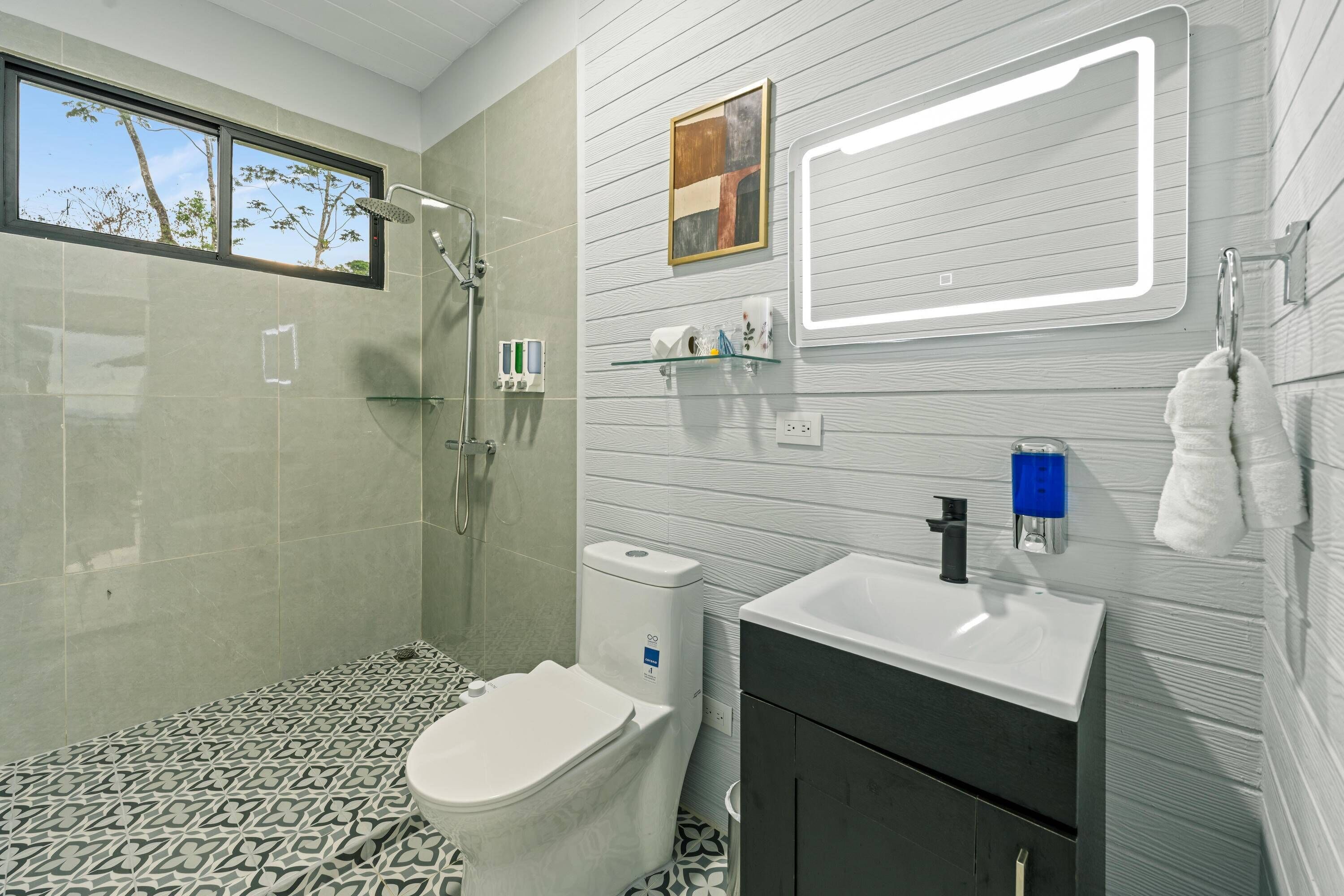 Ein modernes Badezimmer mit Dusche, Toilette, Waschbecken und einem großen Spiegel.