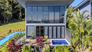 A modern two-story house with large windows, a swimming pool, and tropical plants. - Junglo Resort and Spa (Peñas Blancas)