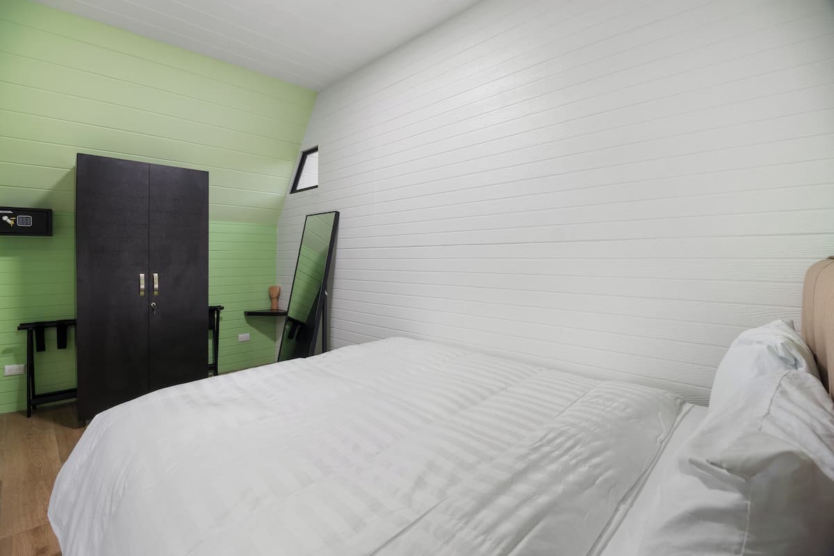 Un dormitorio con cama, armario, espejo y una mesita.
