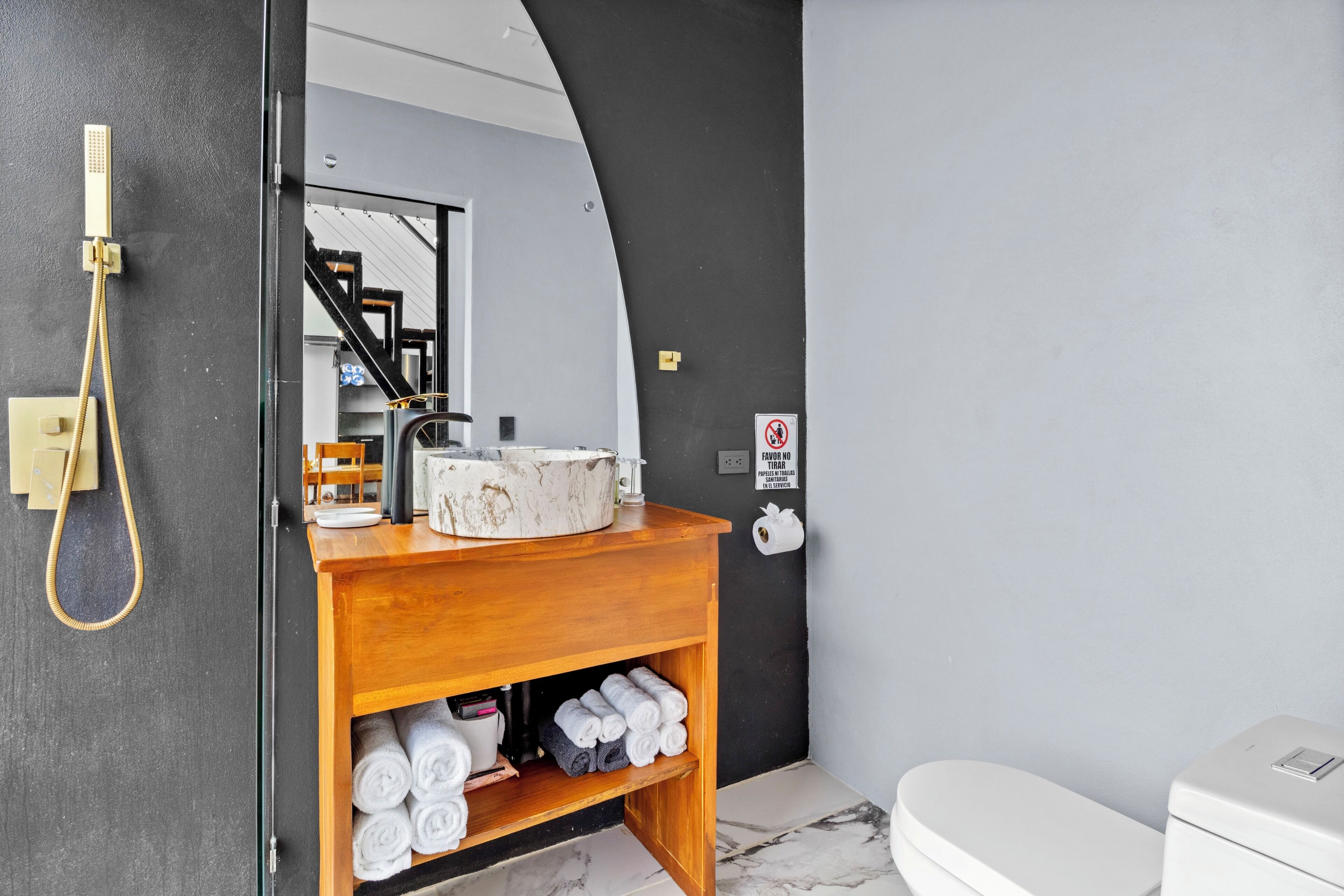 A modern bathroom with a wooden vanity, a toilet, and a shower area.