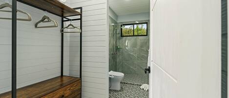 A bathroom with a shower, toilet, and a wooden bench.