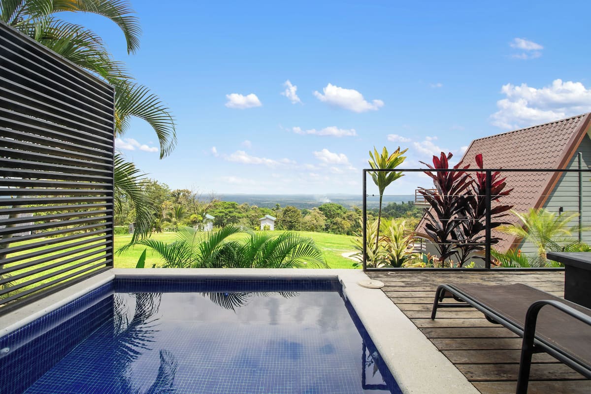 Una piscina con vistas a un paisaje verde y una casa distante.