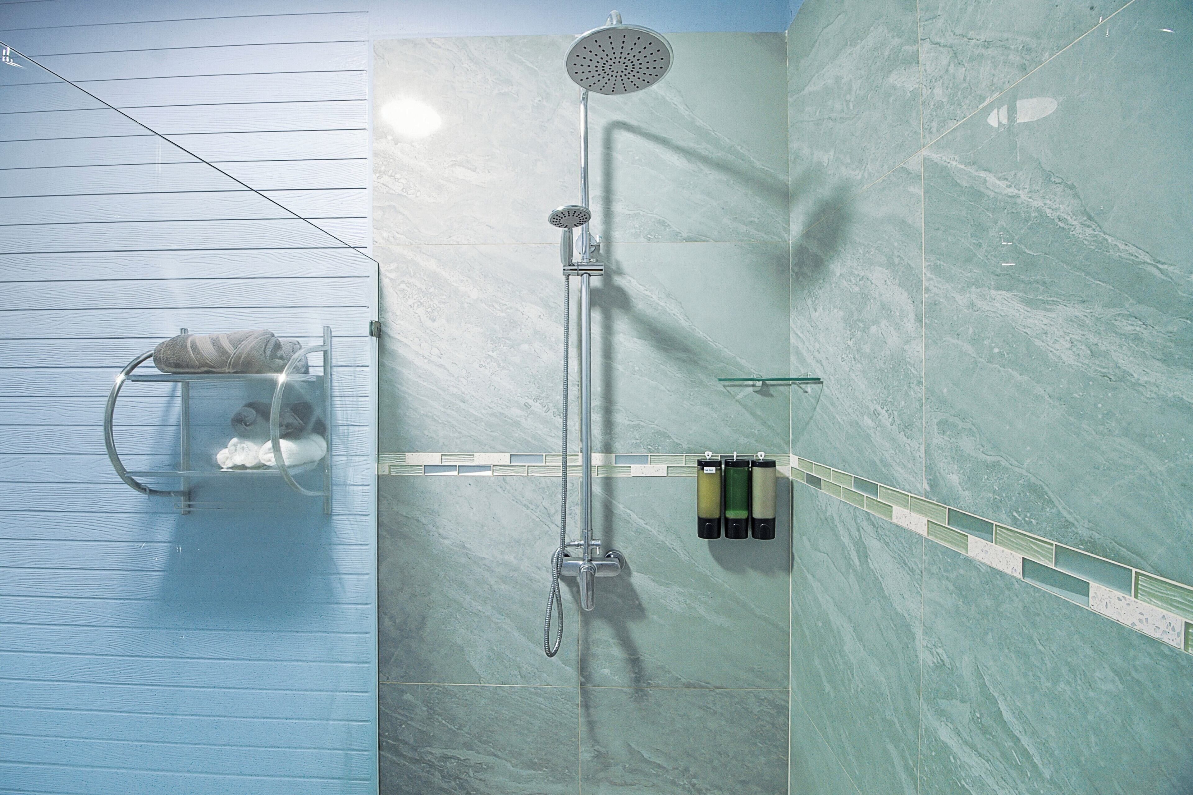 Un bagno con doccia, portasciùmani e box doccia in vetro.