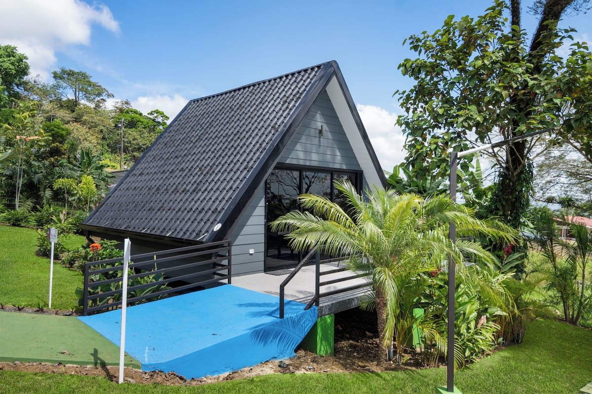 Un edificio moderno de techo triangular con una plataforma azul y una escalera que conduce a la entrada.