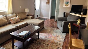 Una sala de estar con sofá, sillón, mesa de centro y televisor.