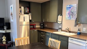 Una cocina moderna con armarios oscuros, una mesa de comedor de madera y un lavavajillas.