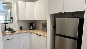 Een moderne keuken met witte kasten, een roestvrijstalen koelkast en een houten aanrecht.