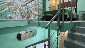 Ein modernes Interieur mit einer Treppe, einer kleinen Essecke mit Tisch und Stühlen sowie einem großen, abstrakten Wandbild.