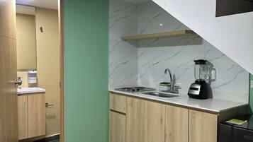 A modern kitchen with wooden cabinets, a marble backsplash, a built-in stove, and a black refrigerator.