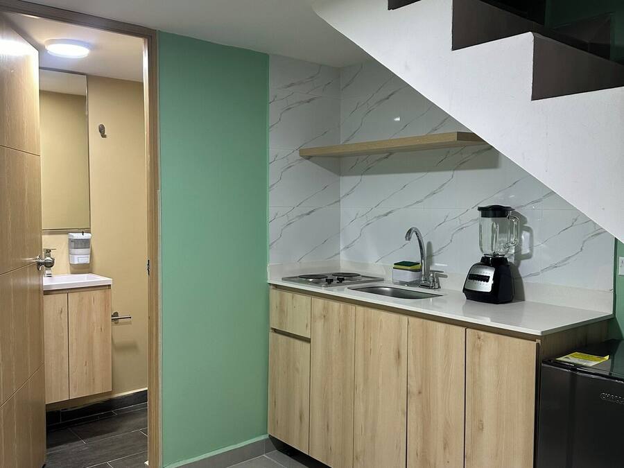 Uma cozinha moderna com armários de madeira, painel de backsplash de mármore, fogão embutido e geladeira preta.