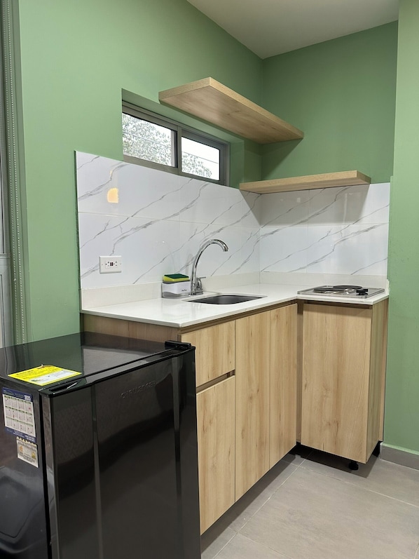 A compact kitchen with a black refrigerator, a sink, and wooden cabinets.