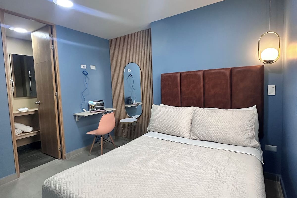 Une chambre d’hôtel comprenant un lit, un bureau, une chaise, un miroir et une armoire.