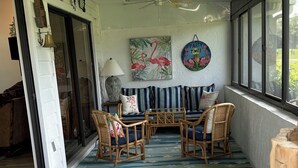 A spacious room with a ceiling fan, a large window, and a view of the outdoors. There are several wicker chairs and a table in the center. - Immaculate 3 bedroom villa: updated amenities on the Prestigious IMG Golf Course (Bradenton)