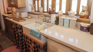 Una cucina con mobili in legno, un lavello doppio e diversi oggetti da cucina sul piano di lavoro.