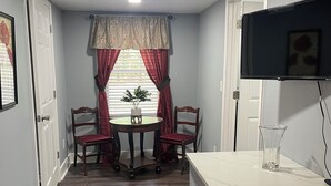 A room with a dining table, chairs, a TV mounted on the wall, and a small kitchen counter. - Peaceful 3-Bedroom Retreat in Huger, SC – Gateway to the Lowcountry (Huger)